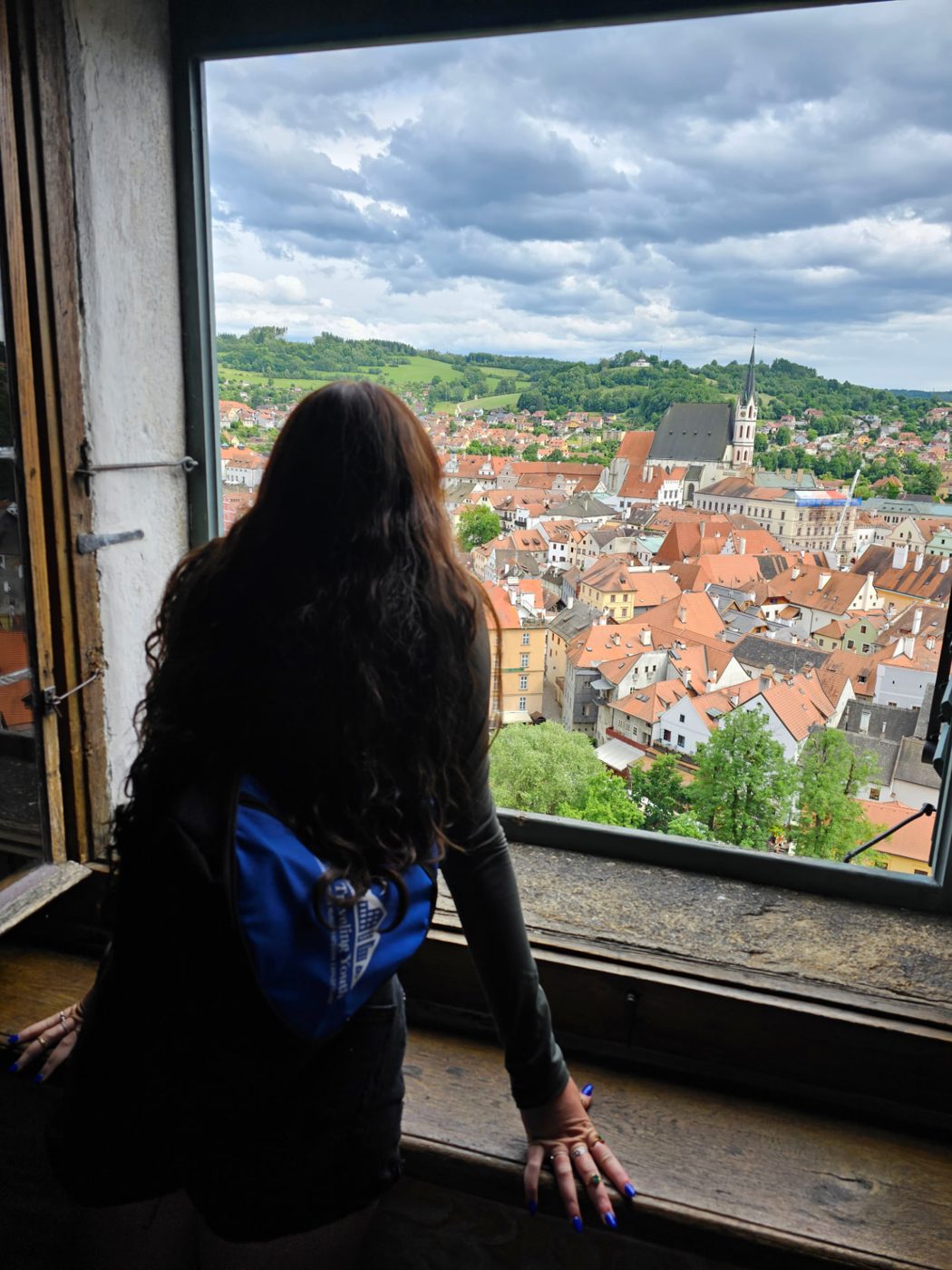 A TTY student looking out a castle window over the rooftops of Český Krumlov
